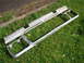 1979 Ford Bronco - A chrome grille assembly lies on a grassy area next to a paved surface.