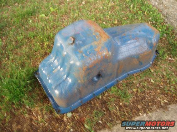 Blue painted oil pan with rust spots, resting on grass and concrete