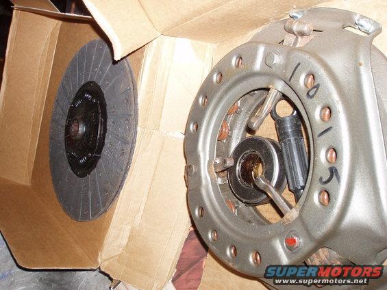 Clutch disc in box next to pressure plate assembly with handwritten numbers