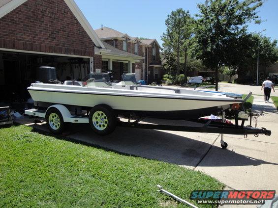 White boat on a trailer parked in a driveway