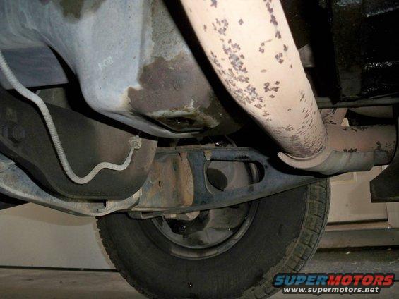 Underside of a vehicle showing exhaust pipe, oil pan, and tire