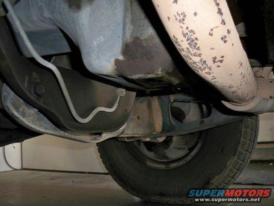 Underside view of vehicle showing suspension, exhaust pipe, and tire