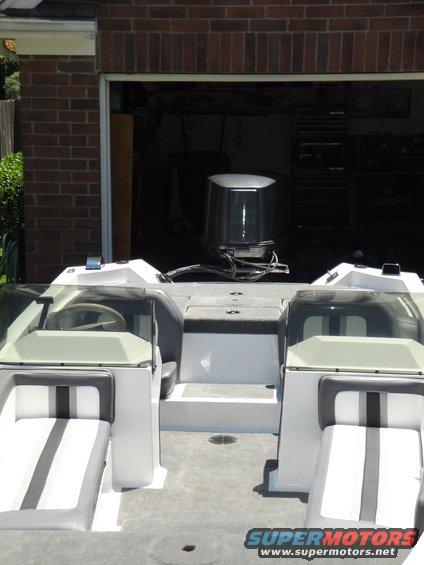 Boat interior with two rows of seats and an outboard motor visible in the background