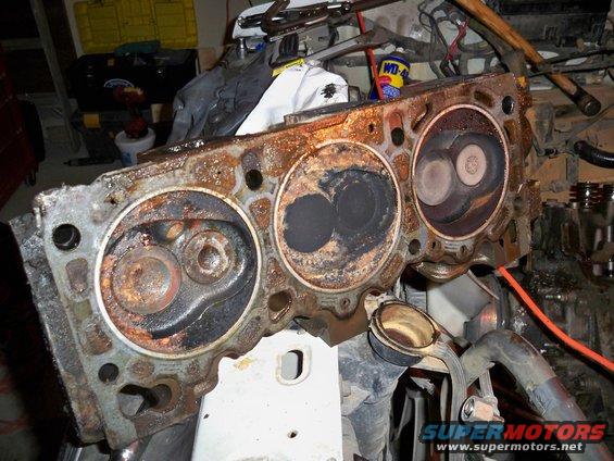 Rusted engine cylinder head with visible valves and combustion chambers