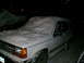 1994 Ford Explorer - A white 1994 Ford Explorer is partially covered in snow during a nighttime snowfall.