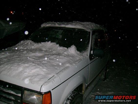 1994 Ford Explorer covered in snow at night, front passenger side visible