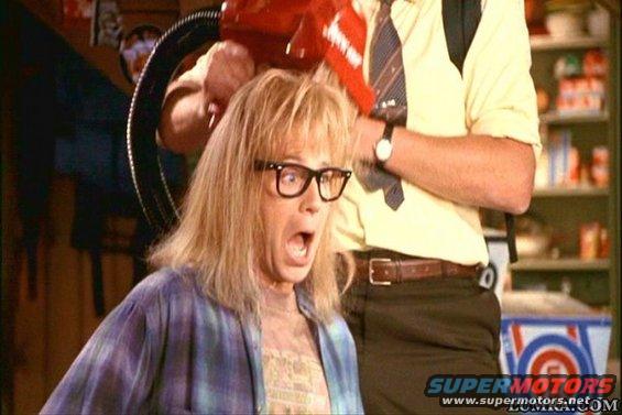 Person with blonde hair and glasses reacting as another person uses a red hair dryer on their head