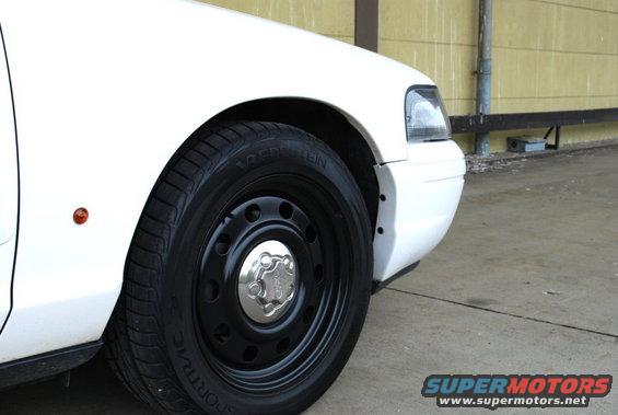 White 1998 Ford Crown Victoria front fender and wheel with black steel rim and chrome hubcap
