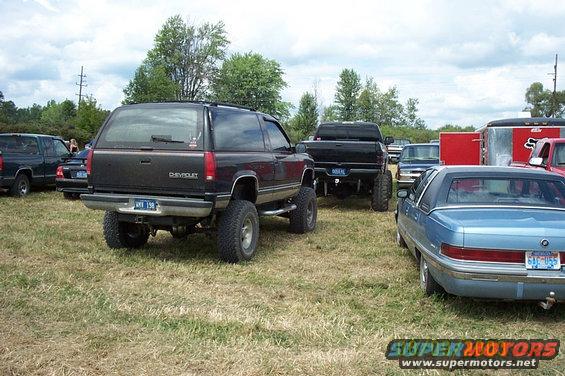 Black Chevrolet SUV lifted with large tires, rear view, license plate visible