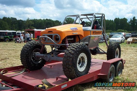Orange off-road buggy with roll cage on a red trailer. BFGoodrich tires visible