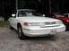 1995 Ford Crown Victoria - A white 1995 Ford Crown Victoria is parked on a gravel lot with a red car visible behind it.