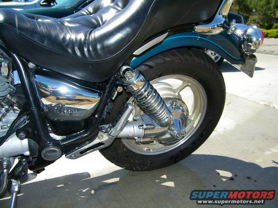Close-up of a motorcycle's rear wheel, shock, and seat. Chrome accents are visible