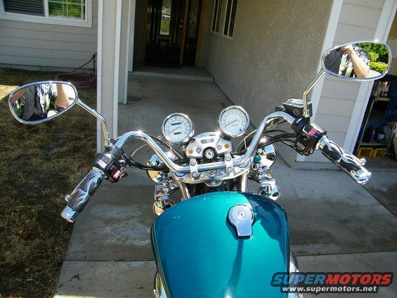 Teal motorcycle tank and chrome handlebars with flame grips and dual gauges