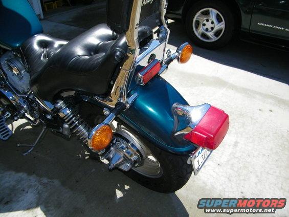 Close-up of a motorcycle's black leather seat and teal rear fender with chrome accents