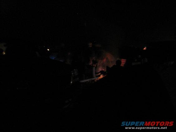 Dark scene with multiple vehicles and a campfire