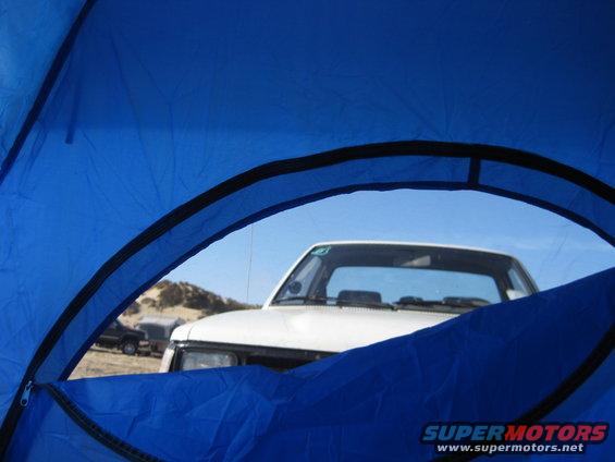 White 1989 Toyota Pickup/SR5 parked near a tent with a desert landscape behind it