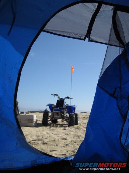 Blue ATV on a sandy beach with an orange flag