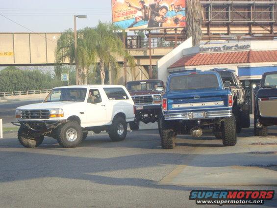 White Ford Bronco with aftermarket bumper and large tires, viewed from the front-left