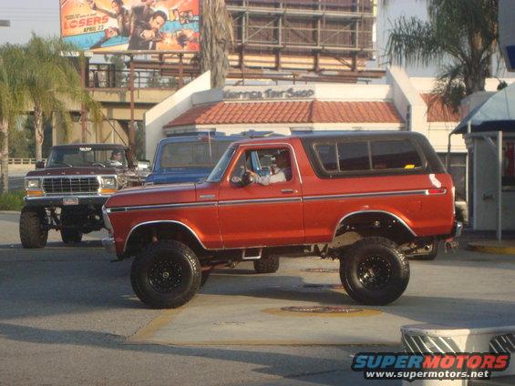 Orange Ford Bronco with lifted suspension and black wheels