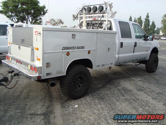 Silver Ford Super Duty truck with a service body, "CERVANTES RACING" text on the side, and a rack with lights on top