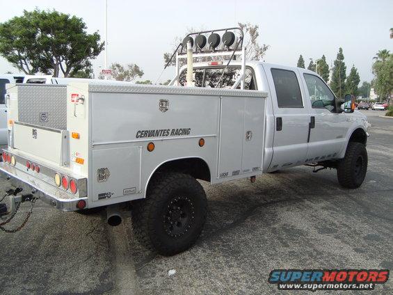 Silver pickup truck with utility bed, off-road tires, and light bar on roof. Text 'CERVANTES RACING' visible on the side