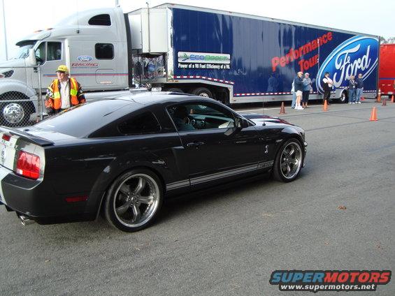 Black 2007 Ford Mustang Shelby GT500 parked next to a Ford Performance Tour trailer