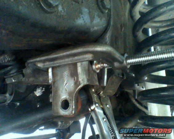 Close-up of a metal bracket and coil spring, held by vise grips