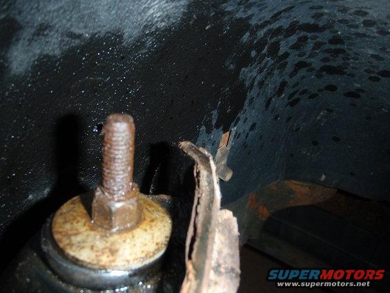 Close-up of rusty bolt and metal bracket, likely from a vehicle's undercarriage