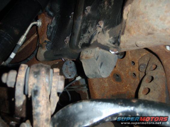 Close-up of rusty suspension parts, including a shock absorber and metal brackets