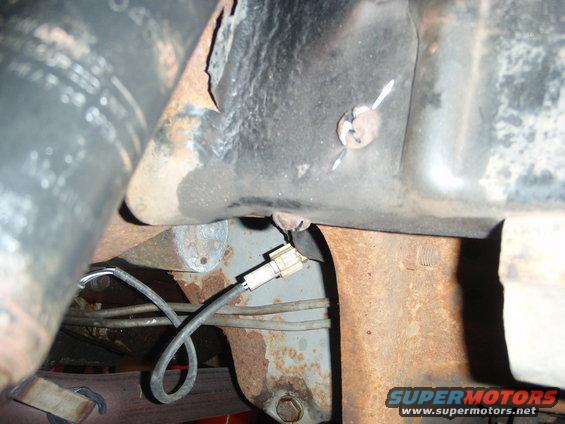 Undercarriage of a vehicle with rusty metal frame, a wire harness, and a Supermotors.net logo
