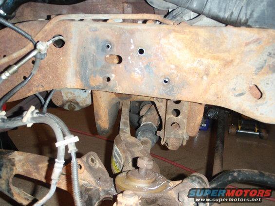 Close-up of heavily rusted vehicle frame with suspension components visible