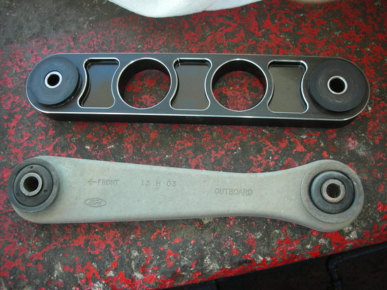 Ford control arm with "13 H 03" stamp next to aftermarket part