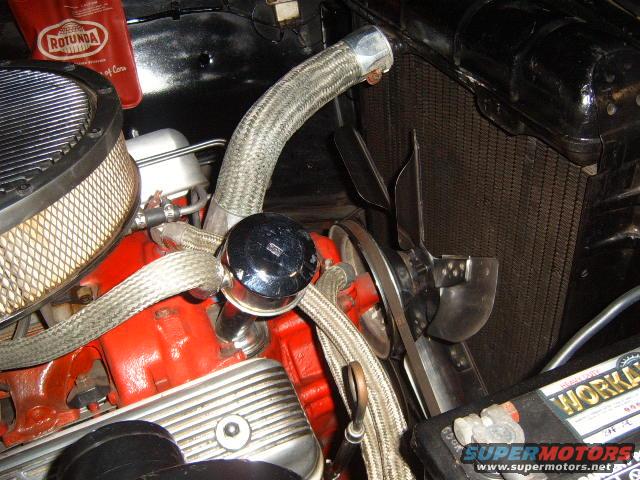 Engine bay showing radiator, fan, air cleaner, and part of the engine block. Rotunda oil can is visible