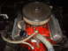 1956 Ford Fairlane - Close-up view of a vehicle's engine compartment, a prominent chrome air cleaner and bright red engine block.