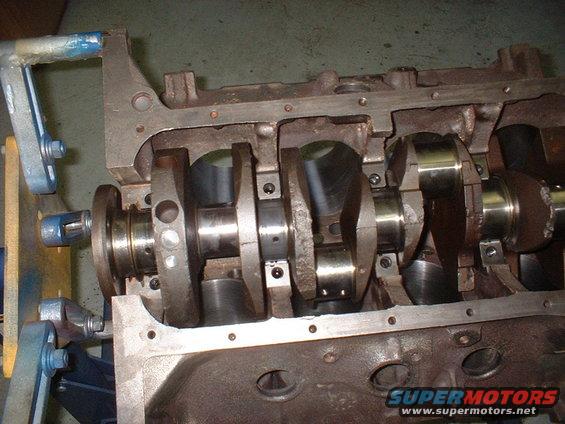Engine block with crankshaft and connecting rods visible, mounted on a stand