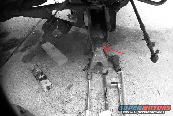 bronco-001.jpg The last thing that remains are the two ball joints themselves.  What you see in this photo - Knuckle with ball joints still pressed in is gone.  Tools on the bottom (from left to rt): Pickle fork to release the lower ball joint, a 1" and 5/16 wrench and for the upper ball joint nut, and 1/2" drive ratchet with (I think) a 1" and 1/8 socket.  What you don't see in this photo: a can of MAPP gas to heat the nuts, about an hour of hard work and sweat, along with some cursing.  My ball joints hadn't been changed in a loooong time.  Tons of rust.  I had an old can of propane gas I was using to heat the nuts to crack them.  Couldn't budge them...propane not hot enough.  Got a can of MAPP gas - that stuff burns hot.  After about two minutes of heating the nuts with MAPP gas, they came off much easier.

Just because you've taken the ball joint nuts off doesn't mean the knuckle just falls off the control arm.  Like I said, the ball joint is tapered and pressure (and rust) is holding it in.  That's why you need the pickle fork.  10 bucks...well worth it, believe me.  The 1" and 5/16 open/boxed wrench is a size I didn't have.  I went looking for that size in a socket, and couldn't find it.  I bought the wrench at Sears for $30.  Since it's only taking the upper ball joint nut off, there is plenty of room and you can use the boxed end.  The lower ball joint nut needs the socket, as you're putting it thru the hole in the knuckle to get at the nut.  I don't remember exactly what size it is, but it's part of my standard sears purchased 1/2" drive socket set - I didn't have to buy that one.  

To take the knuckle off / release the ball joints, first you crack the upper ball joint nut.  Like I said, use penetrating oil and heat (be carefull, the oil if flammable).  Loosen the upper nut, but don't take it all the way off.  Now on to the bottom nut.  Put the rachet thru the hole in the knuckle (where you pulled the axle thru) and again apply heat and oil, then a lot of pressure - you see my home made breaker bar in the photo.  Once that nut is off (completely off), now use the pickle fork on the lower ball joint.  It goes right under the control arm, inbetween the control arm and the ball joint (red arrow).  As you bang it in, it exerts pressure downward on the ball joint, releaseing it from the hole.  When it releases, the whole knuckle will want to fall out and down...on your toes.  This is why you don't take the upper ball joint nut off completely.  It will stop the knuckle from fall on your toes...unscrew the upper nut and lower the knuckle to remove it from the control arm.  