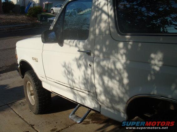 White 1992 Ford Bronco side view, showing the front fender badge and a step bar