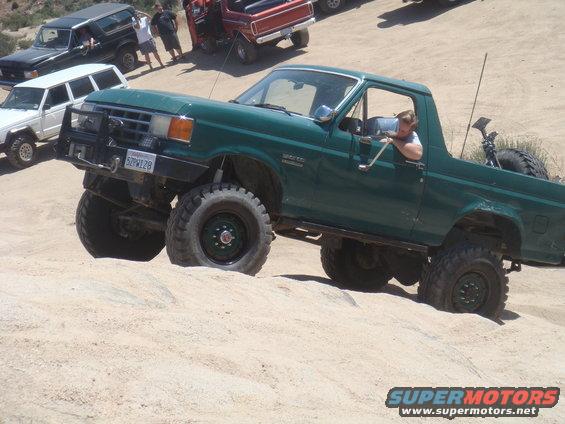 Green 1992 Ford Bronco climbing sand dune