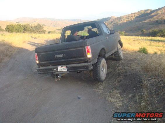 Black 1992 Ford Bronco rear view on a dirt road