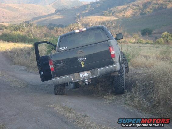 Black Ford F-150 with lifted suspension and open door on dirt road