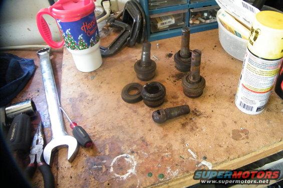 bronco-007.jpg The dead soldiers...  See the ball joint out of the cup?  That was my last one... With the forth hit with the pickle fork, the knuckle drops and I think I'm done.  Nope... Another hour of oil, heat, banging and fun.

If you've come this far, and actually observed what you're working on, you should understand things now and be comfortable putting it back together.  I say this because I had a few photos of everything going back on, and they got deleted.  

I did run into one problem on one side.  When you put the knuckle back on, you have to finger tighten both the upper and lower ball joint nuts, then crank down the lower nut to 30-40 ft lbs. (you'll need a tourque wrench for most of the nuts and bolts going back on).  After the lower is at 30-40 lbs, then the top nut get it till 95 ft lbs. (check your manual for ft lbs numbers).  Then go back to the bottom and finish that to 95 ft lbs.  At some point during tighting the lower ball joint nut, it stud is going to start spinning with the nut.  You need more pressure - from the bottom, to push that stud taper tighter in hole.  Use your jack and pump it up below the lower ball joint.  This worked fine for me on one side, but not the other.  I couldn't get enough pressure with just the jack.  I had to use the ball joint press, and that was fun.  With the knuckle on, plus the ratchet to tighten the nut, there wasn't much room at all for the press.  It took a while and a lot of patience, but I got it.

Once the knuckle is on, in goes the axle, followed by the spindle.  Rotor back on the spindle.  Now the first three things going back on inside the hub are the inner lock nut, the lock washer and the outter lock nut.  The inner has a little peg sticking out of one side.  This peg must be pointing at you when going back on.   First, crank this lock nut with the special beer can wrench to 50 ft lbs.  Back it off, then tighten back to 45 - 40 ft lbs.  The 50 ft lbs sets the rotor against the spindle and sets the two bearings in the rotor nice and snug.

Other things of note during installation - the spindle nuts get cranked to a certain tourque (mine was 50 ft lbs)...easy does it putting the axles back in.  Don't damage the oil seal on the diff or bust up the splines on end of the axle...change the U joints on the axle if needed.  You want do 3/4 of this all over again in the future?....Don't forget the CV boot on the passanger side axle.  And replenish any gear oil that may have leaked from the diff when you pulled the axles.  