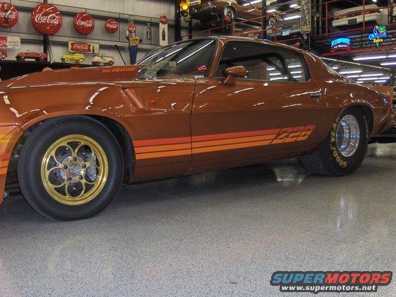 Side view of a brown drag car with orange stripes and Z28 badging. It has gold racing wheels and Goodyear tires