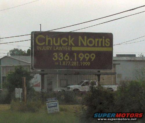 Billboard for Chuck Norris Injury Lawyer with phone numbers 336.1999 and 1.877.281.1999. A white pickup truck is visible behind the billboard