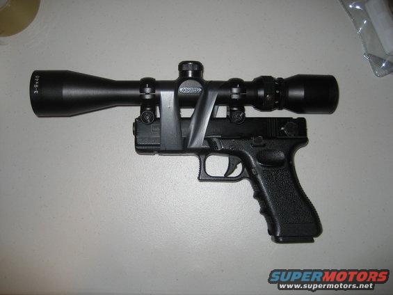 Pistol with a scope mounted on top using a black strap