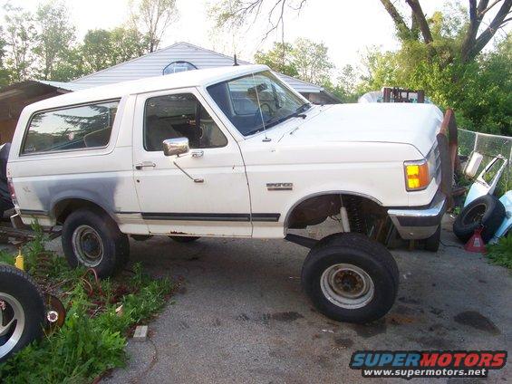 White Ford Bronco with lifted suspension and large tires parked outside a house