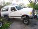 1989 Ford Bronco - This lifted Ford Bronco appears to be from the early 1990s, not 1989, and is parked in a driveway with some spare tires nearby.