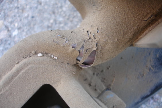Close-up of heavily rusted and corroded metal tubing, possibly part of a vehicle's subframe