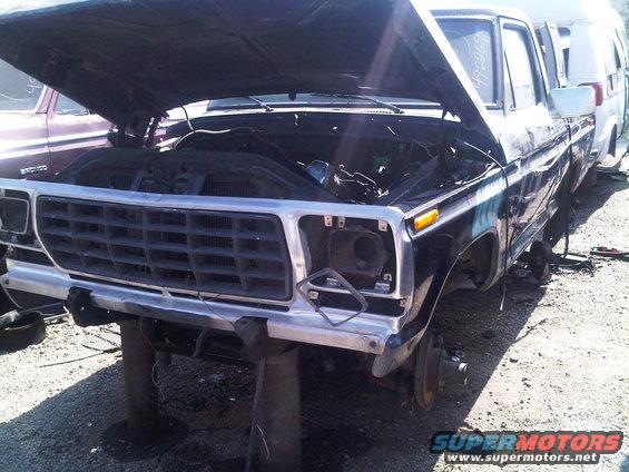 Black SUV with hood open, missing headlights, and grille from the early 1980s