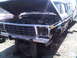 1986 Ford Bronco - This black SUV, likely from the early 1980s, sits in a junkyard with its hood open and missing headlights.