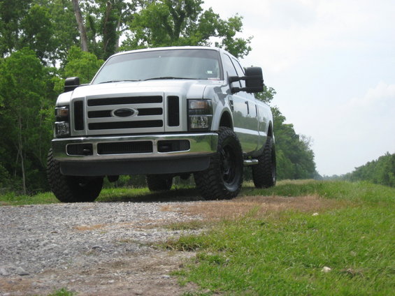 Silver 2008 Ford F-250 pickup truck with large tires parked on a gravel road